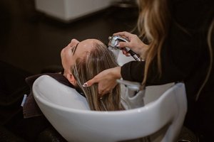 Woman having her hair rinsed after a hairdresser applies toner
